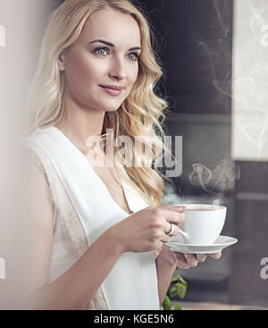 Portrait of a pretty blond lady drinking a cup of coffee Stock Photo