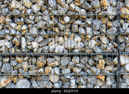 Wire Gabion Rock Fence. Metal Cage filled with rocks. Texture background of rock fence with cage. Stock Photo