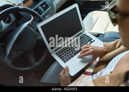 High angle closeup of unrecognizable successful man using laptop sitting inside of expensive car, copy space Stock Photo