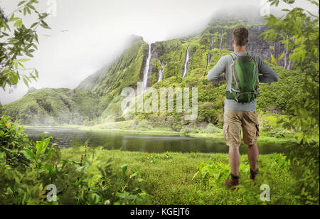 Young hiker in front of an exotic waterfall Stock Photo