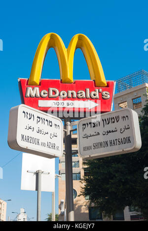 Israel The Holy Land Tel Aviv Jaffa Yafo road street sign signs Arabic Hebrew Ivrit English scene McDonald's blue sky modern high rise apartments Stock Photo