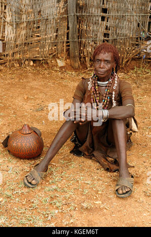 DIMEKA, OMO VALLEY, ETHIOPIA - JULY 27: Portrait of the woman from Hamer people resting by the fence in transit to the local marketplace in Dimeka, Om Stock Photo