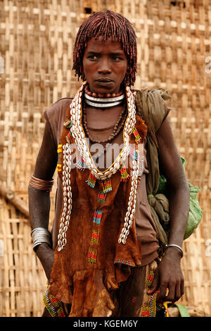 DIMEKA, OMO VALLEY, ETHIOPIA - JULY 27: Portrait of the woman from Hamer people resting by the fence in transit to the local marketplace in Dimeka, Om Stock Photo