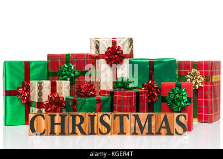 The word Christmas in wooden letters in front of gift wrapped presents, cut out on a white background. Stock Photo