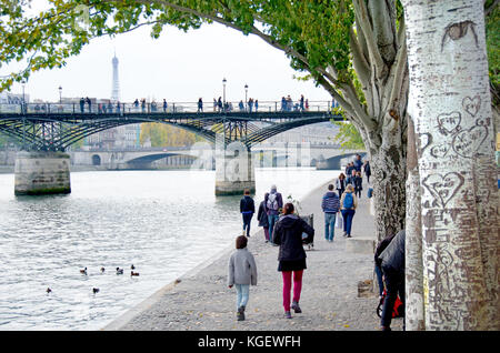 Paris, France. People walking along the north bank of the River Seine, Pont des Arts and Eiffel Tower behind Stock Photo