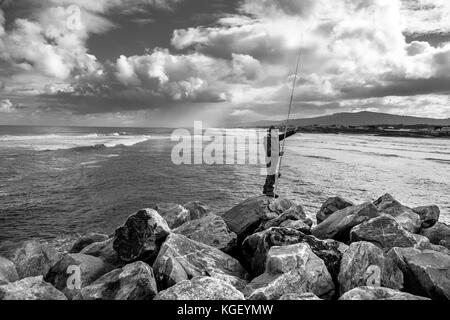 Fisherman fishing a stormy day with the sea in the background Stock Photo