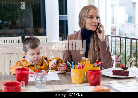 Restaurant mom with son talking on the phone Stock Photo