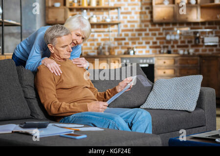 Nice caring woman standing behind his husband Stock Photo