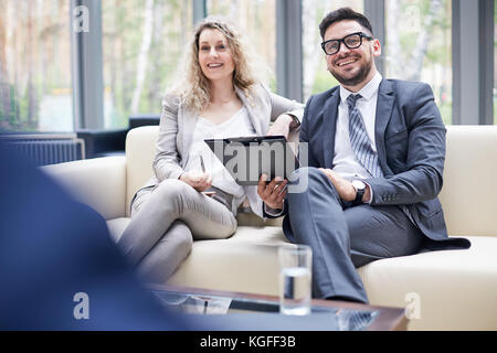 Group portrait of cheerful colleagues in formalwear having fun while discussing start-up project at spacious boardroom with panoramic windows Stock Photo