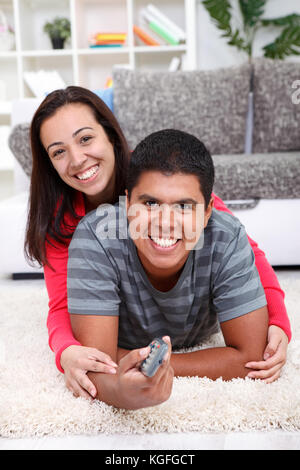 Smiling  couple watching  TV on floor at home Stock Photo