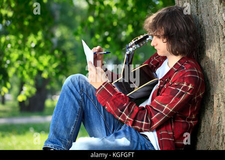 Man composing song on guitar in park Stock Photo
