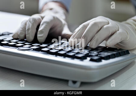 Computer hacker hand in glove working on laptop Stock Photo
