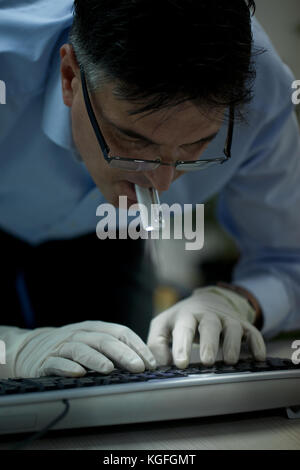 Burglar holding flashlight in mouth and stealing data from a laptop concept for computer security, corporate or identity theft Stock Photo