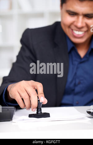 Young businessman at his desk stamping document Stock Photo