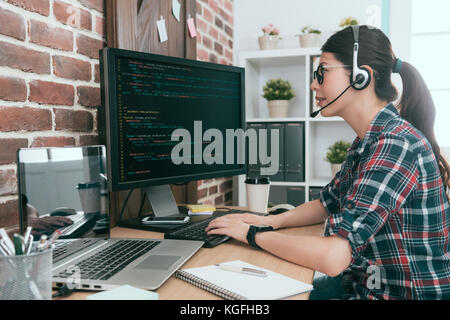 smiling friendly woman operator monitoring customer computer through remote system and using computer typing data code to solving problem. Stock Photo
