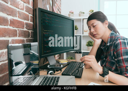 pretty elegant lady computer developer sitting in front of working computer design coding long time and feeling tired napping on desk. Stock Photo