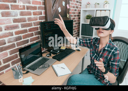 professional young computer programmer wearing VR technology goggles working and using hands touching screen organizing coding data to develop new onl Stock Photo