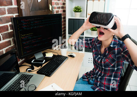beautiful happy programmer woman using virtual reality goggles watching 3D simulation video feeling surprised. Stock Photo