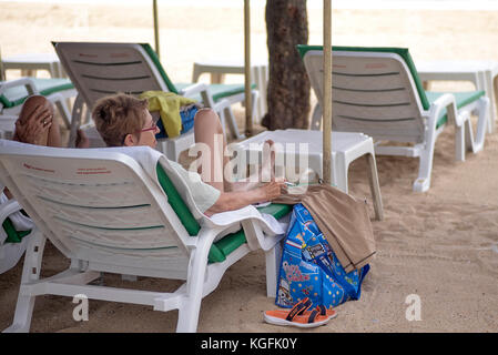 Woman smoking a cigarette on a Thailand beach. The government has passed legislation against this imposing fines and possible imprisonment Stock Photo