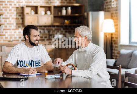 Happy old man discussing his treatment with a positive young volunteer Stock Photo