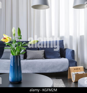 Simple blue vase with flowers on coffee table in living room Stock Photo