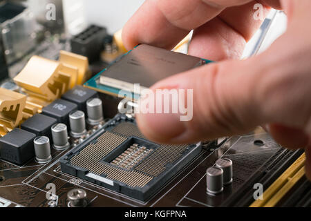 Technician plug in CPU microprocessor to motherboard socket Stock Photo