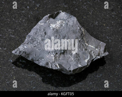 macro shooting of natural mineral rock specimen - raw shungite shale stone on dark granite background from Tolvuya district, Karelia, Russia Stock Photo