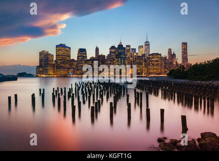 manhattan skyline New York skyline stormy sunset sky above the skyscrapers with Brooklyn old pier 1 wooden pilings New York City New York State USA Stock Photo