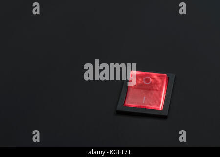 Illuminated red electrical switch on black background - potential metaphor for 'stopping', switching, on-off, stopping & starting things in general. Stock Photo