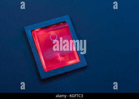 Illuminated red electrical switch on black background - potential metaphor for 'stopping', switching, on-off, stopping & starting things in general. Stock Photo