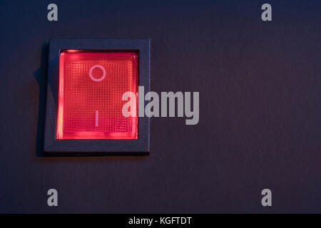 Illuminated red electrical switch on black background - potential metaphor for 'stopping', switching, on-off, stopping & starting things in general. Stock Photo