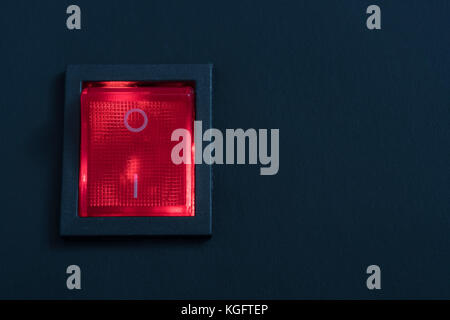 Illuminated red electrical switch on black background - potential metaphor for 'stopping', switching, on-off, stopping & starting things in general. Stock Photo
