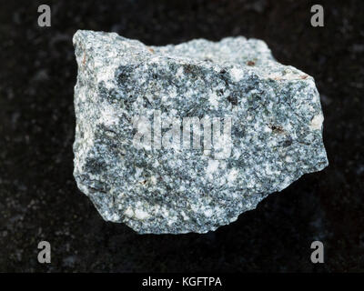 macro shooting of natural mineral rock specimen - raw Diorite stone on dark granite background Stock Photo