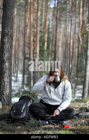 A man in a campaign drinks tea. A young traveler in the woods ca Stock Photo