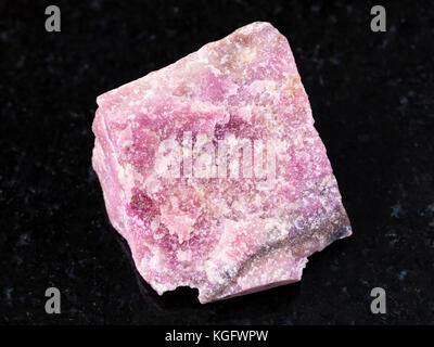 macro shooting of natural mineral rock specimen - rough rhodonite stone on dark granite background from Ural Mountains Stock Photo