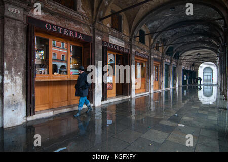 Venice, Italy. 07th November, 2017.  A man walks in the high water under a portico during an high tide on November 7, 2017 in Venice, Italy. Stock Photo