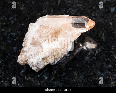 macro shooting of natural mineral rock specimen - rough crystal of topaz gemstone on dark granite background from Brazil Stock Photo