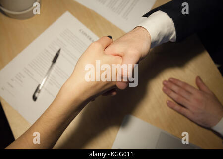 Business handshake. Close up top view of two businesspeople shaking hands after signing contract. Human resources manager hiring new employee at job i Stock Photo