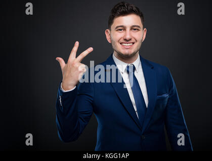 Attractive and friendly executive manager counting three fingers and smiling Stock Photo