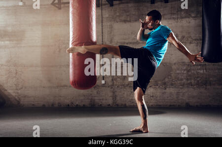 Muscular man punching with leg a boxing bag on cross fit training at the gym Stock Photo Alamy