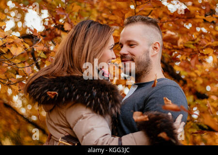 Portrait of a beautiful young couple in sunny forest in autumn colors. They are at embraced. Stock Photo