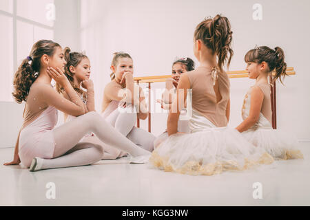 Group of a little girls in dresses taking a break from ballet class. Stock Photo