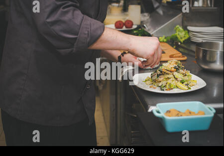 A chef prepares food in the kitchen of a restaurant