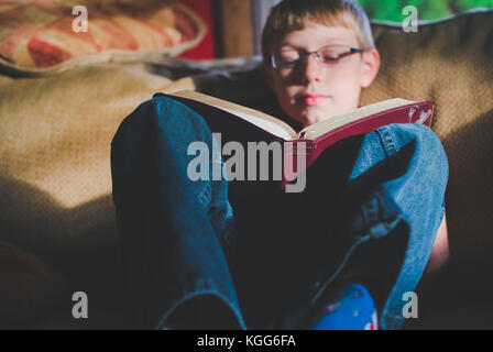10-11 year old boy reading a book Stock Photo