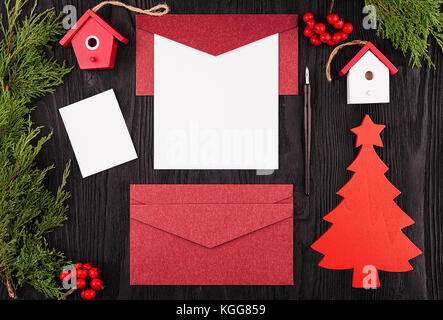 White sheet of paper on a red texture envelope with Christmas decorations. View from above. Copy space Stock Photo