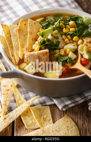 Homemade tortilla soup with chicken and vegetables close-up in a pot on the table. vertical Stock Photo