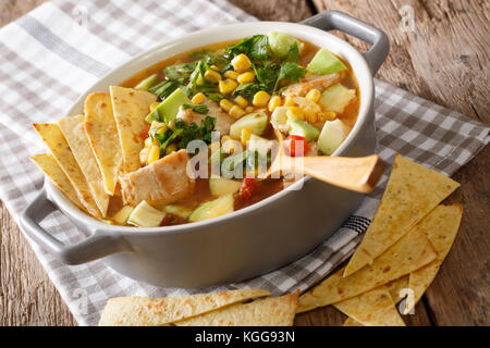 Mexican tortilla soup with chicken and vegetables close-up in a saucepan on a table. horizontal Stock Photo