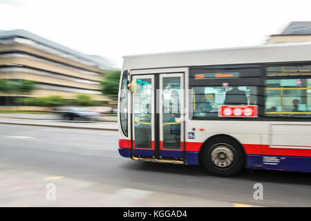 Bus panning. Glasgow, Ireland. Bus is moving fast on a street. Driver concentrating on a road ahead of him. People, passengers sitting in a bus. Publi Stock Photo