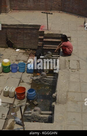 Nepalese girl waiting in line to collect drinking water with jerrycan in ancient fountain, Kathmandu, Nepal. water shortage, drought, after earthquake Stock Photo
