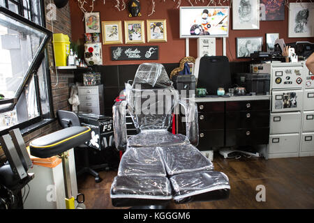 A Tattoo Artist at Work,A tattoo artist inks a designed onto the back of a local girl in his studio in Leeds. Stock Photo